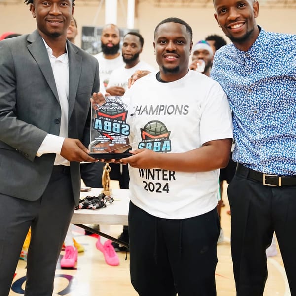 Men holding a basketball championship trophy indoors