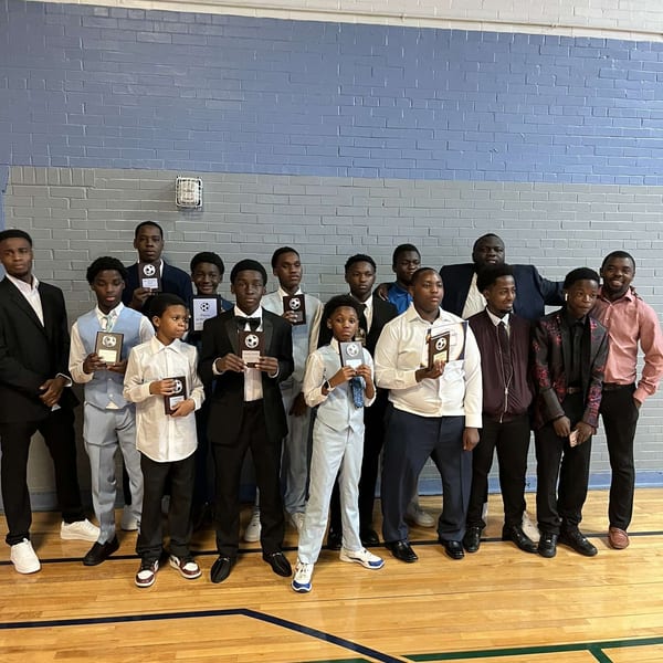 Group holding awards on a gymnasium floor