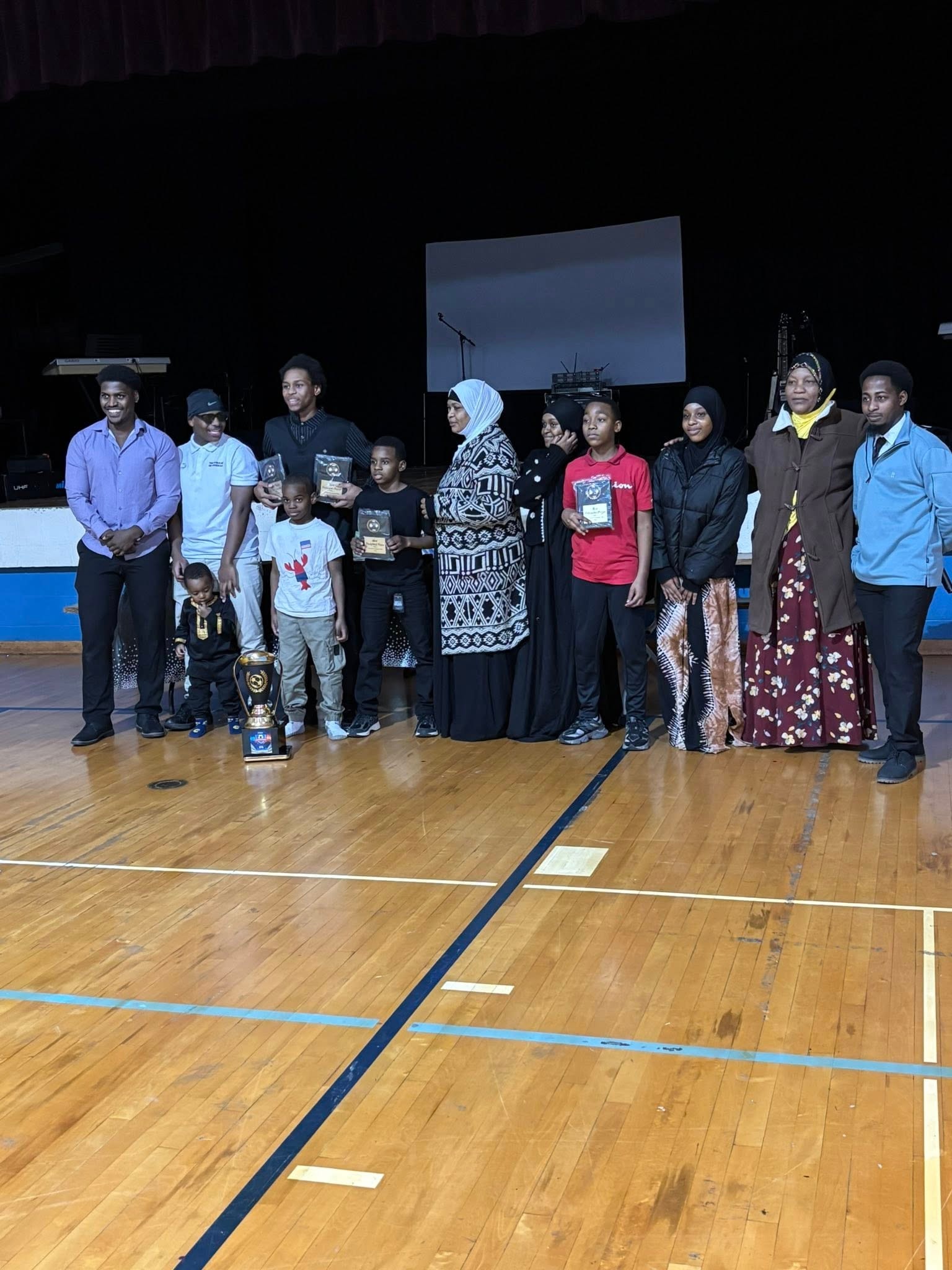 Group posing with a trophy on a gymnasium court