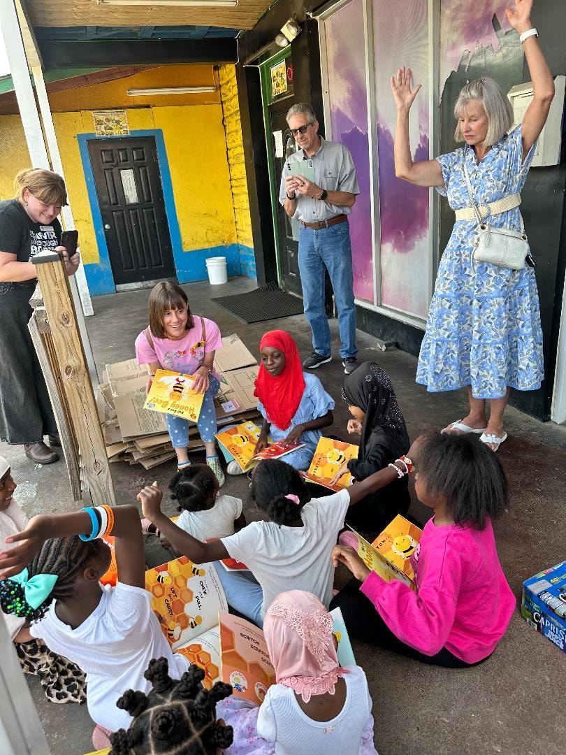 Adults distributing books to children outdoors