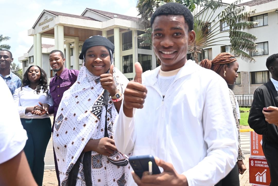 Group of people giving thumbs up outside a building